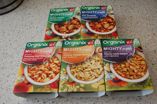 Five Organix Mighty Meals boxes for toddlers are arranged on a countertop, showcasing delicious organic baby food in flavours like beef bolognese, creamy chicken pasta, lamb hotpot, pasta in tomato sauce, and pork casserole.