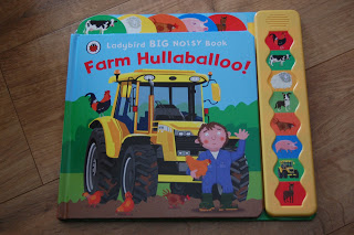A children’s book titled "Farm Hullabaloo!" features a yellow tractor, animals, and a farmer on the cover. Sound buttons on the side let kids bring the fun of Farm Hullabaloo to life with each farm animal or object.