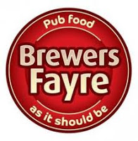 Red circular logo for Turnpike Brewers Fayre with "Brewers Fayre" in bold beige letters. Around the edge, "Pub food" appears at the top and "as it should be" at the bottom, both written in yellow.