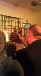 A man in a suit and tie looks at a group of people, possibly presenting an HTC Flyer review or discussing insights from his latest tablet review.