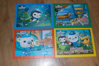Four completed Octonauts 4-in-a-box jigsaw puzzles are laid out on a wooden floor, each featuring colourful underwater scenes with much-loved cartoon characters from the Octonauts series.