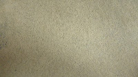 A close-up view of a beige textured surface, possibly suede or soft fabric, with a slightly uneven appearance and subtle variations in colour—ideal for testing the effectiveness of Rug Doctor Urine Eliminator.