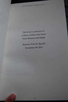 A U Star Novels book dedication page reads: "This book is dedicated to: Callum, Nathan and James. From Mummy and Daddy. Because You're So Special. 5 November 2012." A hand holds the bottom left corner—perfect for a heartfelt review.