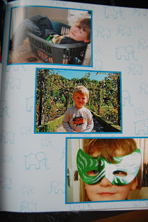 A collage of three photos: a child lying in a laundry basket, the same child standing outdoors in a grey shirt, and a close-up wearing a green and white mask. The light blue animal background gives this photo book layout a playful Crewe vibe.