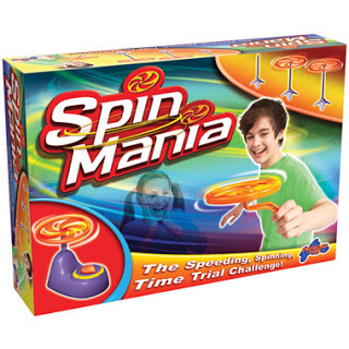 Box of the Spin Mania game showing a boy using a spinning top launcher, with colourful tops and a girl smiling in the background. Perfect for Christmas fun or as a Day 8 gift in the 12 Days of Christmas! The tagline reads, "The Speeding, Spinning, Time Trial Challenge!.