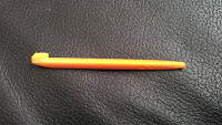 An orange pen with a cap lies horizontally on a textured black surface, reminiscent of the vibrant design found in Vtech MobiGo 2 devices.