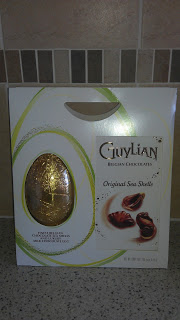 A box of Guylian Belgian Chocolates featuring a gold-foil Easter Egg and an image of chocolate sea shells on the packaging, displayed on a kitchen worktop.