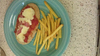 A turquoise plate holds a slice of bread topped with gooey cheese and tomato sauce, served with a side of McCain’s chips for extra food fun—all set on a speckled worktop perfect for any foodie’s delight.