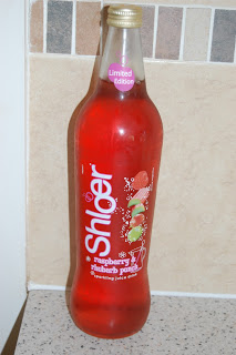 A glass bottle of Shloer Raspberry Rhubarb Punch, labelled as a limited edition, stands on a kitchen worktop with a beige tiled splashback in the background.