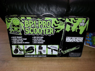 A box for a Madd Gear BP1 Beginner Pro Scooter, featuring green and black graphics, a skull logo, and product details. The box states it is for ages 8 and up and includes images of the scooter and its features.