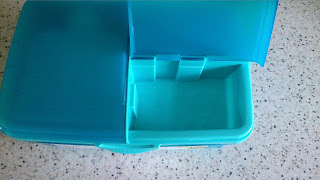 A blue plastic lunchbox from Asda, with one compartment open and the other closed, sits on a speckled worktop—perfect for back to school or stocking up on essential school supplies.