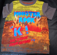 A colourful T-shirt from Mothercare, featuring bold "MONSTER ROCK", "K!", and "THE TERROR FROM BEYOND" text over flames and abstract patterns—perfect for fans of stylish boys' clothes.