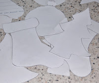 Paper cut-outs of Christmas shapes, including a stocking, tree, bauble, and bell, are scattered on a speckled worktop—perfect inspiration for your next SmART Attack or Shredder Challenge with Fellowes products!.