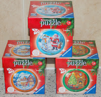 Four Christmas-themed Ravensburger puzzle boxes are stacked in a pyramid shape. Each box features a festive image, including Father Christmas, a snowman, a house, and a decorated Christmas tree—perfect for fans of Christmas puzzles.