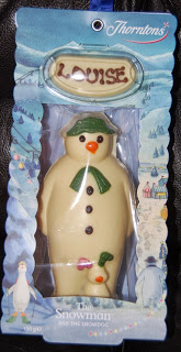 A white chocolate snowman and a small duck, packaged in a wintry-themed Thorntons Christmas box, with a white chocolate name plaque reading “LOUISE” at the top.