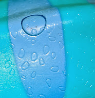 Close-up of water droplets on a smooth, blue and turquoise plastic surface, with light reflecting off the droplets and creating a glossy texture—evoking the vibrant colours of Dinosaur Train toys ready for Christmas morning.
