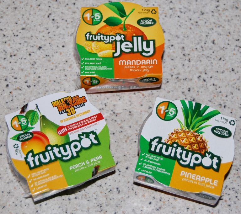Three Fruitypot fruit pots on a speckled worktop: Mandarin jelly, Peach & Pear, and Pineapple—tasty fruit snacks, each labelled "1 of 5 a day" with a spoon included. Perfect for your next Fruitypot review!.