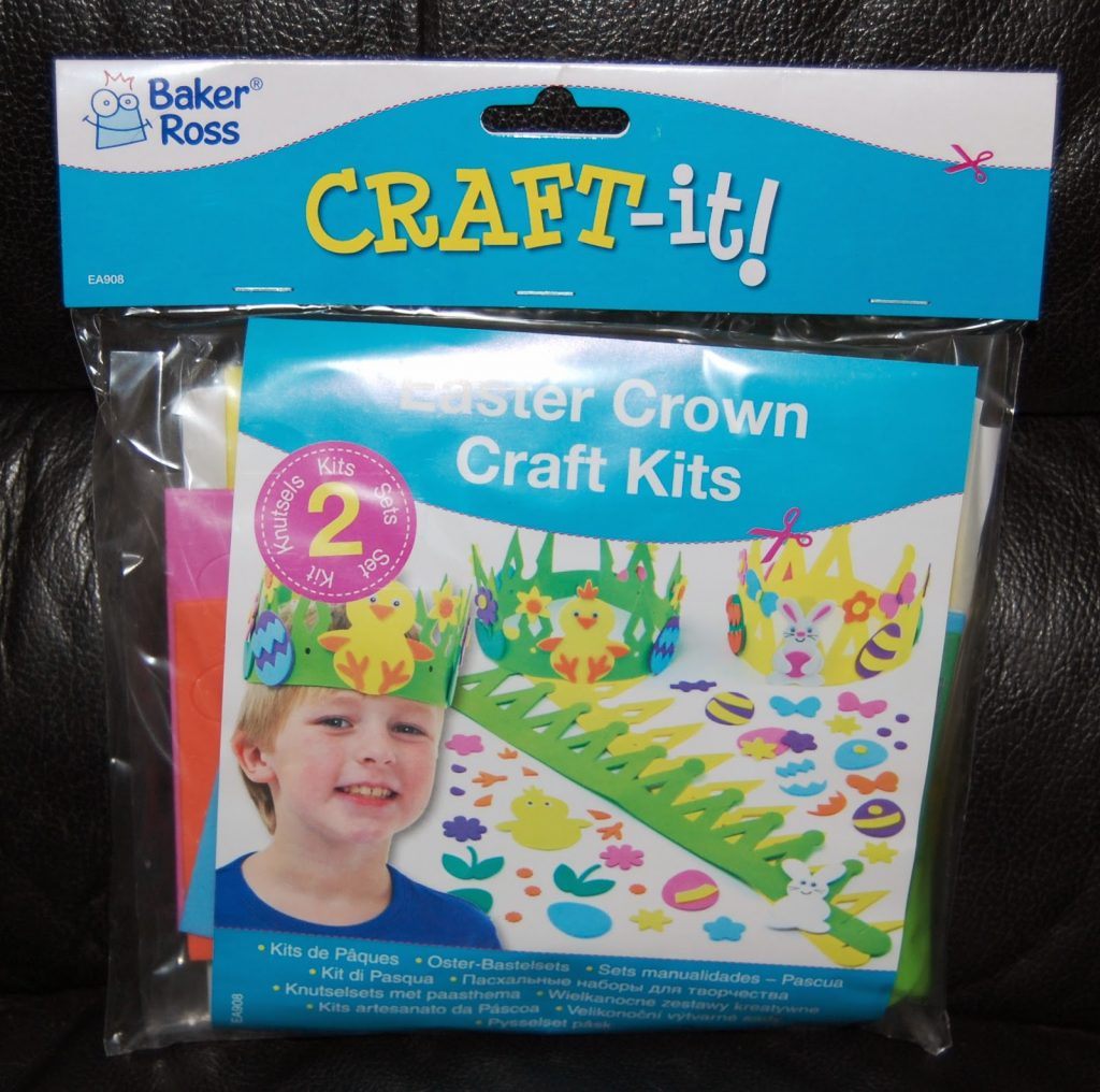 A packaged "Baker Ross CRAFT-it!" Easter Crown Craft Kit, featuring a child wearing a colourful, crafty Easter crown with fun designs. The kit contents are visible through the packaging.