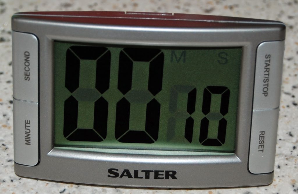 A digital Salter kitchen timer displays 00:18 seconds, perfect for timing your Chocolate Easter Nest creations. The silver timer sits on a speckled worktop, with buttons for SECOND, MINUTE, START/STOP, and RESET below the screen.