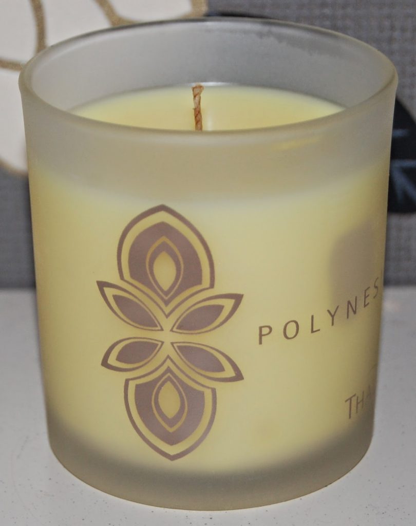 A yellow candle in a frosted glass holder with a brown floral design and the word "POLYNES" partially visible on the side, ideal for promoting a good night's sleep.