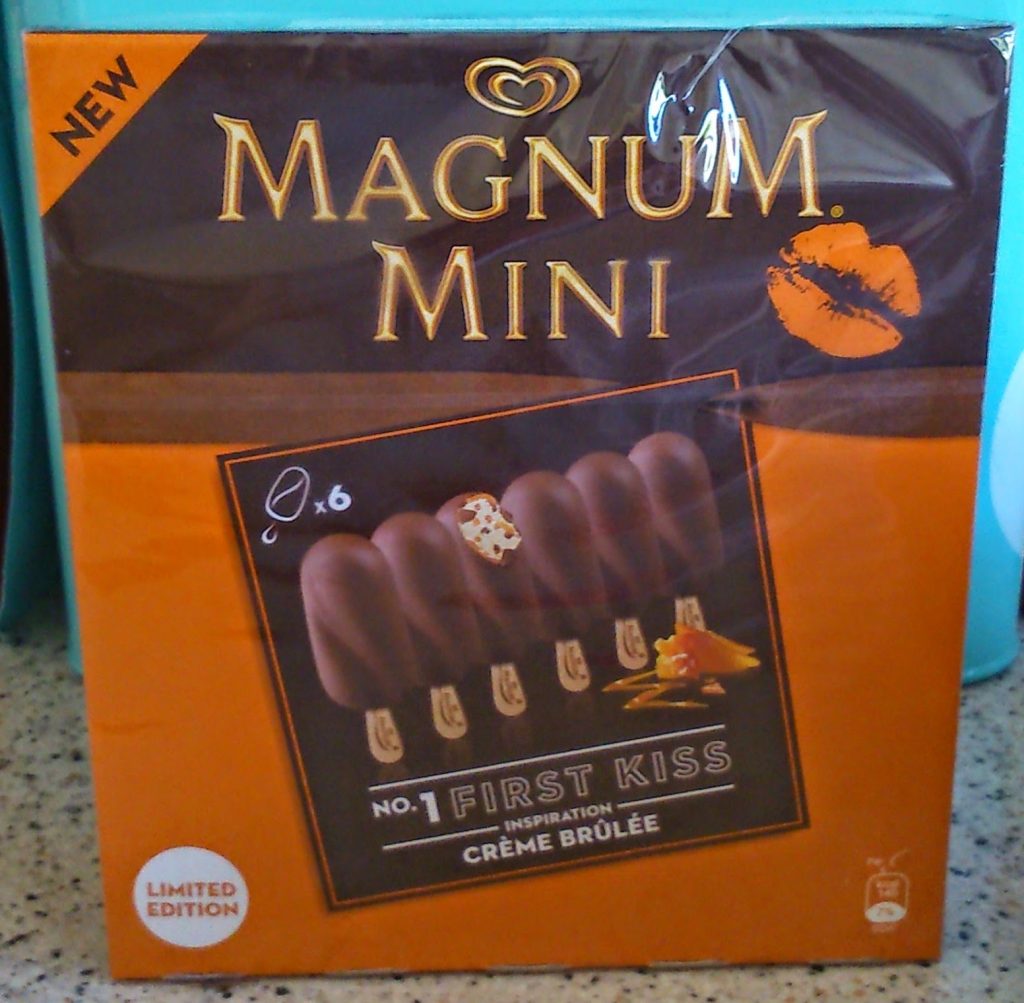 Box of Magnum Mini "First Kiss" crème brûlée ice cream bars, perfect for summer treats. The dark brown and orange packaging features a kiss mark, "Limited Edition" label, and is available now at Ocado. Contains six chocolate-dipped bars.
