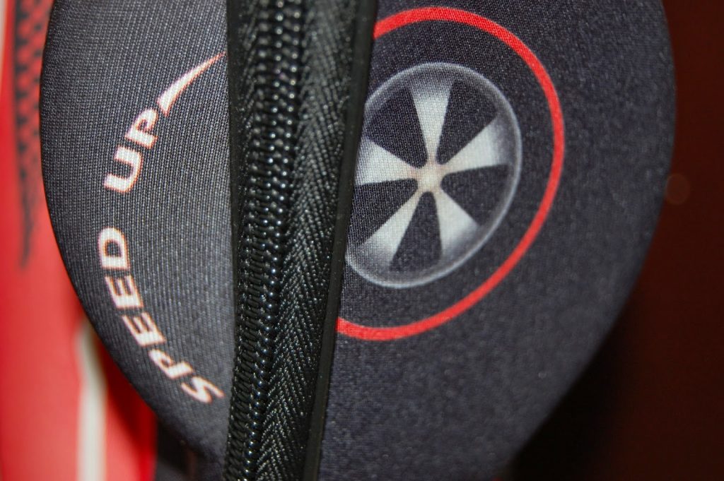 Close-up of a black and red paddle cover displaying a circular design and the words "SPEED UP" along the edge—perfect for travelling light with children. A black zip runs vertically through the centre of the image.