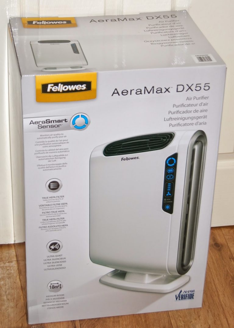 A white and grey Fellowes AeraMax DX55 air purifier in its packaging box, featuring product details, features, and specifications printed on the front in multiple languages—ideal to help improve allergies or address child allergies.
