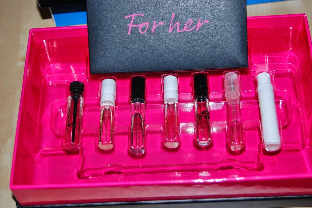 A pink tray holds seven small perfume sample vials and a black card with "For her" in pink letters—an elegant set of fragrances, perfect as thoughtful gifts for her.
