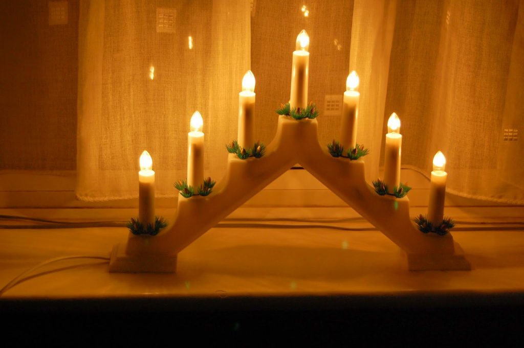 A candleholder with lit candles, perfect for decking the halls and adding a warm touch to your holiday decorating.