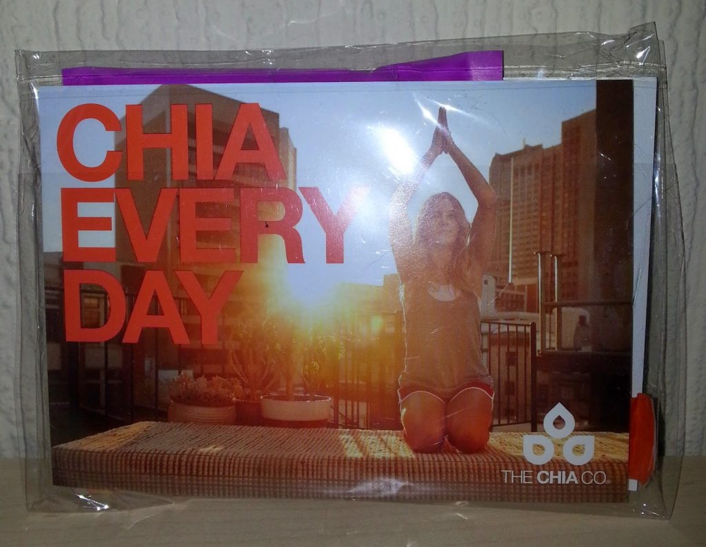 A woman practises yoga on a rooftop at sunrise with city buildings in the background. Large text reads "CHIA EVERY DAY" as she enjoys a healthy start, inspired by her Degustabox snack subscription box. "THE CHIA CO" logo appears in the corner.