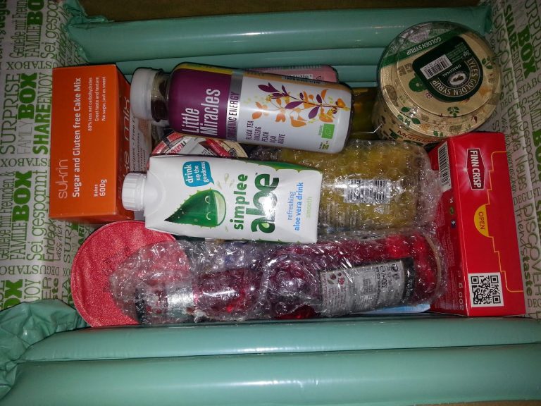 A Degustabox packed with assorted groceries, including coconut water, vitamins, instant soup, gluten-free cake mix, a red packet, jam, and more—discover new flavours each month with this snack subscription!.