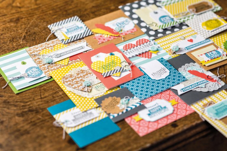 A variety of colourful handmade greeting cards with different patterns, tags, and embellishments are spread out on a wooden surface—plus, you could Win an Everyday Occasions Card Making Kit to create your own heartfelt “thank you” or “congratulations” cards.