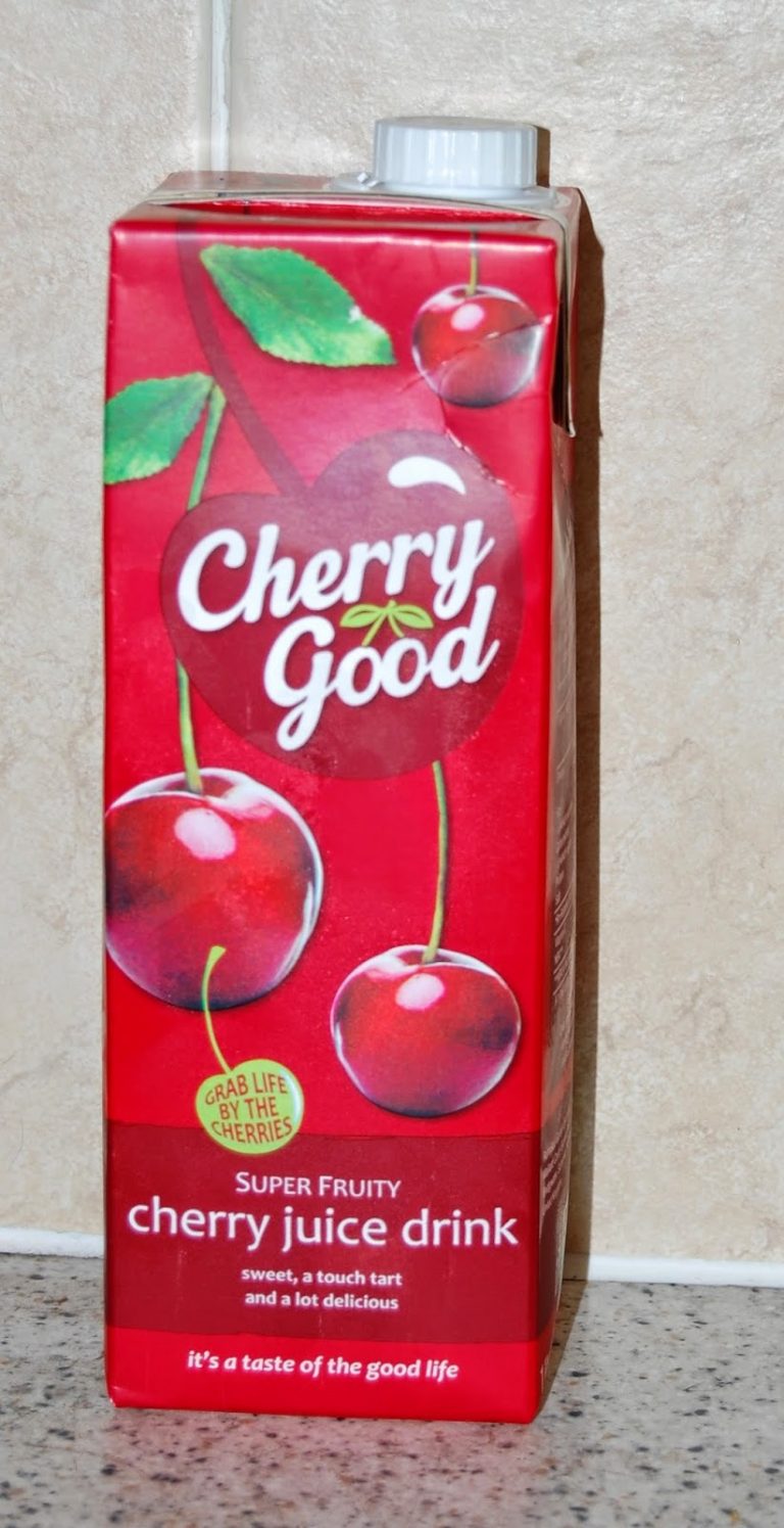 A red carton of Cherry Good cherry juice stands on a worktop. The packaging features images of cherries, the brand name, and the text “Super Fruity cherry juice drink,” highlighting it as a tasty and healthy drink choice.