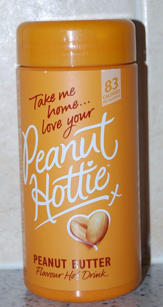 A yellow-orange container labelled "Peanut Hottie Peanut Butter Flavour Hot Drink" with the text "Take me home... love your Peanut Hottie." Featured in a Degustabox review, it shows two peanuts and lists 83 calories per serving.
