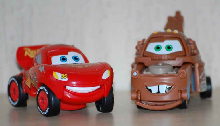Two toy cars from the film "Cars"—a red racing car with a big smile and number 95, and a brown tow truck with green eyes and buck teeth—make fun Alternative Easter Gifts, placed side by side on a light surface.