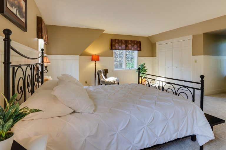 a metal frame bed made up with white bed coverswith