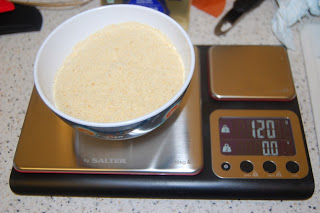 A white bowl filled with a light yellow powder sits on a digital kitchen scale, displaying a weight of 120 grams—a setup perfect for tackling a Heston-inspired Pear Tarte Tatin challenge on your speckled worktop.