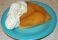 A slice of Heston’s Pear Tarte Tatin is served on a turquoise plate with a generous swirl of whipped cream on the side, offering a delicious challenge for your taste buds.