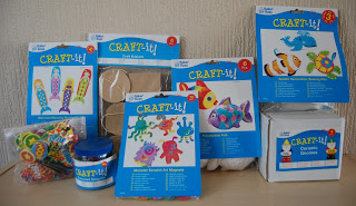 A fun selection of Craft-It! children’s crafting kits and supplies—including foam shapes, beaded items, paint, and packs for making fish, sea creatures, and ceramic figures—arranged upright on a table for half-term creativity.