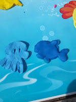Two blue Plasticine Softeez figures, one shaped like an octopus and the other like a fish, rest on a blue surface with water and bubble designs. Perfect for sharing at your next Twitter Party!.