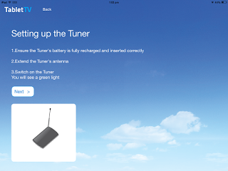 A TabletTV screen displays setup instructions for a tuner, guiding users to recharge the battery, extend the aerial, and switch it on. The review image shows the tuner with its aerial against a sky filled with clouds.