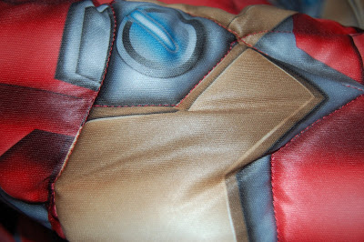 Close-up of a fabric with a printed design in red, gold, and blue, resembling part of a stylised Iron Man mask. The padded, shiny material gives an authentic feel for any Iron Man costume review.
