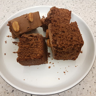 Four pieces of chocolate cake with a few peanuts on top sit on a white plate, placed on a speckled worktop. Some cake crumbs are scattered around the pieces—an irresistible addition to your favourite Christmas recipes.