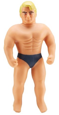 A muscular action figure, like a Mini Stretch Armstrong, with blond hair and black pants, stands with arms bent and fists clenched—truly a Real Cool Dude facing forwards.