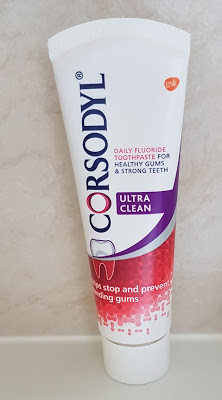 A tube of Corsodyl Ultra Clean daily fluoride toothpaste, designed for gum health and strong teeth, with red and purple accents and text stating it helps stop and prevent bleeding gums.