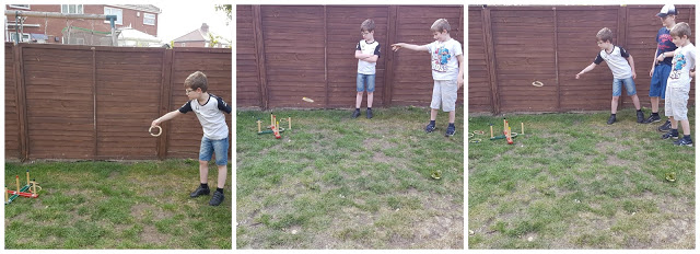 Three boys are playing a hoopla game on a grassy lawn in front of a wooden fence. A plaster peeks out from under one boy’s sleeve as he throws a ring, while the others watch and wait for their turn.