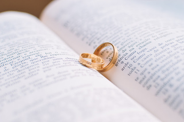 Two gold wedding rings rest on an open book, forming a heart-shaped shadow—one of those small wedding details that make your big day unforgettable.