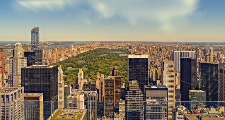 Aerial view of Midtown Manhattan skyscrapers with Central Park in the background on a sunny day in New York, capturing the vibrant energy of the city.