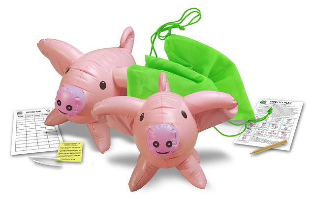 Two inflatable pink pig toys with smiling faces, children's favourites, are placed next to a green drawstring bag, a score sheet, an instruction sheet, a yellow note, and two pencils.