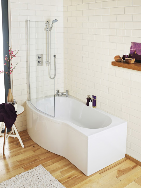 Modern, family friendly bathroom with a white curved bath, glass shower screen, and wall-mounted showerhead. Wooden floor, white subway tile walls, and a shelf with candles and decor add a cosy touch.